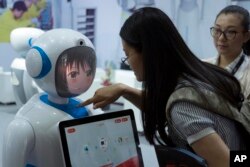 Women interact near a robot designed by Chinese robotics company Pangolin at the Consumer Electronics Show Asia 2018 in Shanghai, China on June 15, 2018.
