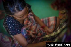 Seorang anak perempuan yang sedang bersiap untuk menyusui bayinya sebagai ilustrasi. (Photo: AFP/Yusuf Wahil)