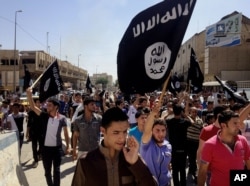 FILE - In this June 16, 2014, file photo, demonstrators chant pro-Islamic State group slogans as they carry the group's flags in front of the provincial government headquarters in Mosul, Iraq.