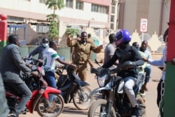 FILE - An army soldier asks people to disperse as they gather outside Guillaume Ouedraogo army camp to show their support for the military after Burkina Faso President Roch Kabore was detained at a military camp in Ouagadougou, Burkina Faso, Jan. 24, 2022