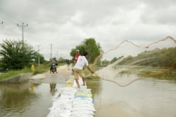 A man casts his fishing net out into a flooded tributary to the Prek Thnaot River that has flooded the Prek Kampeus commune, Dangkoa district, Phnom Penh, Cambodia, on Oct. 14, 2020. (Malis Tum/VOA Khmer)