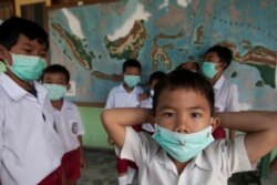 Para siswa sekolah dasar menggunakan masker berdiri di depan peta Indonesia di dalam kelas mereka di Desa Candi Binangun di Sleman, Yogyakarta 2 November 2010. (Foto: REUTERS/Dwi Oblo)
