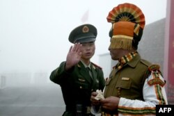 Seorang tentara China memberi isyarat saat berdiri di dekat seorang tentara India di perbatasan antara kedua negara. (Foto: AFP)