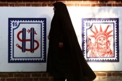 Seorang perempuan berjalan melintas lukisan mural anti-Amerika di dinding bekas Kedutaan AS di Teheran, Irak, 3 Januari 2020. (Foto: Nazanin Tabatabaee/WANA via Reuters)