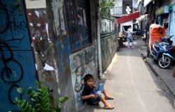 Seorang anak duduk di gang di sekitar rumahnya di Jakarta, 12 Oktober 2019. (Foto: AFP)