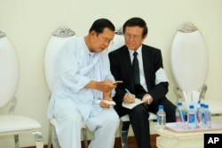 រូបឯកសារ៖ លោកនាយករដ្ឋមន្ត្រី ហ៊ុន សែន (ឆ្វេង) និយាយជាមួយនឹងលោក កឹម សុខា មេដឹកនាំគណបក្សសង្គ្រោះជាតិដែលត្រូវបានតុលាការកំពូលរំលាយ ក្នុងពិធីបុណ្យសពម្ដាយក្មេករបស់ លោក ហ៊ុន សែន ក្នុងរាជធានីភ្នំពេញ ថ្ងៃទី៥ ខែឧសភា ឆ្នាំ២០២០។ (Pool via AP)