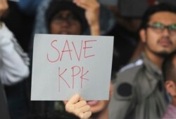 Seorang pendukung KPK mengacungkan poster dalam aksi protes penangkapan Wakil Ketua Komisi Pemberantasan Korupsi Bambang Widjojanto oleh polisi, di luar kantor KPK di Jakarta, Jumat, 23 Januari 2015. (Foto: AP/Tatan Syuflana)