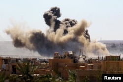 FILE - Smoke rises from the last besieged neighborhood in the village of Baghuz, Deir el-Zour province, Syria, March 18, 2019.
