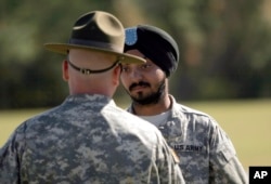 FILE - U.S. Army Spc. Simran Lamba, right, speaks to his drill sergeant following his graduation from basic combat training at Fort Jackson, S.C., Nov. 10, 2010. Lamba was the first enlisted soldier to be granted a religious accommodation for his Sikh articles of faith since 1984.