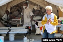 Jane, a tour guide and former nurse with Doctors Without Borders, describes a typical medical tent at a refugee camp at the Forced From Home display in Washington, D.C. (B. Allen/VOA)
