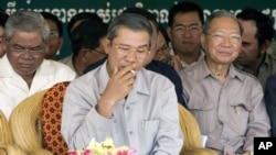 Cambodia's Prime Minister Hun Sen, center, smokes as he sits with Interior Minister Sar Kheng, left, and Finance Minister Keat Chhun, right, file photo.