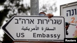 Seorang pekerja memasang papan tanda jalan yang menunjukkan arah ke Kedutaan Besar AS di Yerusalem (8/5).