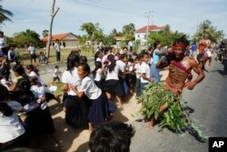FILE - A local youth, front right, scares pupils on a street as he takes part in a ceremony to exorcize evil spirits and pray for rain amid the rice planting season at Pring Ka-ek village, northwest of Phnom Penh, Cambodia, May 22, 2015.