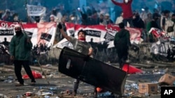 Salah satu pendemo melempar batu ke arah polisi.