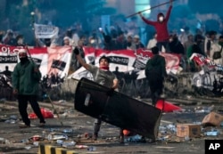 Salah satu pendemo melempar batu ke arah polisi.