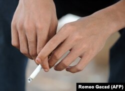 Seorang pemuda memegang rokok yang menyala di sebuah taman di Jakarta. (Foto: AFP/Romeo Gacad)