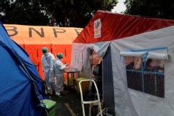 Petugas kesehatan dengan Alat Pelindung Diri (APD) bekerja di antara tenda-tenda darurat yang didirikan di luar ruang gawat darurat untuk menampung kekurangan tempat tidur di rumah sakit milik pemerintah di tengah lonjakan kasus positif COVID-19 di Bekasi, 15 Juli 2021. (REUTERS/Willy Kurniawan/File Photo)