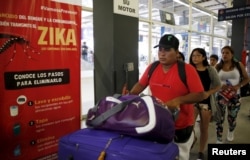 FILE - Travelers walk past a poster with information about the Zika virus during a campaign by Peru's Health Ministry at Plaza Norte bus station in Lima, Peru, Feb. 4, 2016.