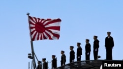 2015年3月25日，日本海军站在即将起航的出云级护卫舰甲板上，这艘军舰即将驶离东京南部的横滨日本联合海上造船厂。