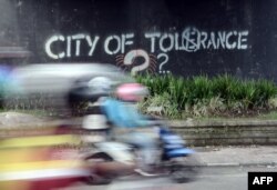 Seorang pengendara melewati grafiti yang menyerukan toleransi di Yogyakarta. (Foto: AFP)