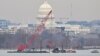A crane removes airplane wreckage from the Potomac River, where American Airlines flight 5342 collided with a US Army military helicopter, near Ronald Reagan Washington National Airport in Arlington, Virginia, on February 3, 2025.