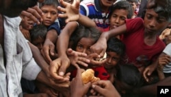 Anak-anak Muslim Rohingya, yang melarikan diri dari Myanmar, mengacungkan tangan mereka untuk menerima makanan yang didistribusikan oleh penduduk setempat di kamp pengungsi darurat Kutupalong di Cox's Bazar, Bangladesh, 30 Agustus 2017. (Foto: dok).