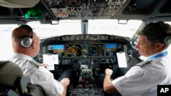 FILE - American Airlines pilot captain Pete Gamble, left, and first officer John Konstanzer conduct a pre-flight check before taking off from Dallas Fort Worth airport on Dec. 2, 2020, in Grapevine, Texas.