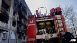A firefighter leans on a fire truck near a damaged residential building following a strike in Dobropillia, Donetsk region, on March 8, 2025, amid the Russian invasion of Ukraine. 
