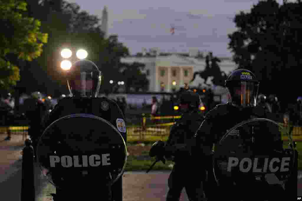 ប៉ូលិស​ប្រដាប់​ដោយ​ឧបករណ៍​ទប់ទល់​នឹង​កុប្បកម្ម ឃ្លាំមើល​កុប្បកម្ម​ខណៈ​ក្រុមបាតុករ​ប្រមូល​ផ្តុំគ្នា ដើម្បី​តវ៉ា​អំពី​ការស្លាប់​របស់​លោក George Floyd នៅ​ថ្ងៃសៅរ៍​ទី ៣០ ខែឧសភា ឆ្នាំ ២០២០ ក្បែរ​សេតវិមាន​ក្នុង​រដ្ឋធានី​វ៉ាស៊ីនតោន។ លោក Floyd បាន​ស្លាប់ បន្ទាប់ពី​ត្រូវបាន​ឃាត់ខ្លួន​ដោយ​ប៉ូលិស​នៅ​ទីក្រុង Minneapolis រដ្ឋមីនីសូតា សហរដ្ឋ​អាមេរិក កាលពី​ថ្ងៃចន្ទ ទី ២៥ ខែឧសភា ឆ្នាំ២០២០។ (AP) 