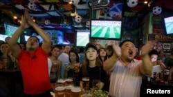 2018年6月14日，人们在北京的一家酒吧观看世界杯甲组俄罗斯对沙特阿拉伯足球比赛，他们看得很投入，聚精会神。