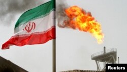 FILE - A gas flare on an oil production platform is seen alongside an Iranian flag in the Gulf, July 25, 2005. On Dec. 19, 2024, the U.S. sanctioned three vessels involved in the trade of Iranian petroleum and petrochemicals.