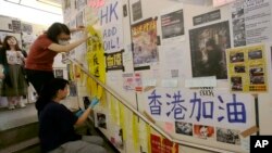 在台湾的香港学生为执行当地政府的指令从一面连侬墙上移走标语。（2019年8月31日）
