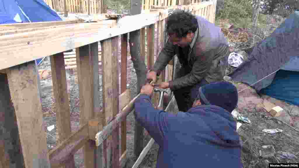 Deux migrants construisent un abri dans dans la &quot;jungle&quot;. Ce camp est situé aux abords de Calais dans le nord de la France, 13 octobre 2015 (Nicolas Pinault/VOA).