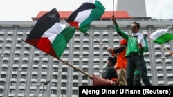 Seorang anggota organisasi buruh Indonesia memegang bendera Palestina saat melakukan aksi protes terhadap Israel di luar gedung PBB di Jakarta, 18 Mei 2021. (Foto: REUTERS/Ajeng Dinar Ulfiana)