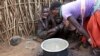 In this photo taken Tuesday, Oct. 17, 2017, a Karamojong woman prepares a meal at her village in the semi-arid savannah region of Karamoja, in northeastern Uganda. (AP/Adelle Kalakouti)