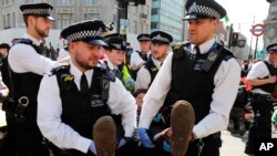 Polisi menangkap para pengunjuk rasa di Oxford Circus di London, Jumat, 19 April 2019. Kelompok Extinction Rebellion menyerukan pekan perlawanan sipil terhadap kegagalan untuk mengatasi penyebab perubahan iklim.
