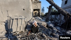 A Palestinian woman sits at the site of an Israeli strike on a house, amid the Israel-Hamas conflict, in Deir al-Balah in the central Gaza Strip, Aug. 7, 2024.