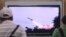 FILE - People watch a TV news program showing the missile launch conducted by North Korea.
