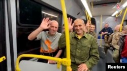 25일 포로 교환을 통해 풀려난 러시아 장병들이 귀환 버스에서 웃음을 짓고 있다.
