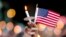 A mourner holds up an American flag and a candle during a vigil for a fatal shooting at an Orlando nightclub, June 12, 2016, in Atlanta.