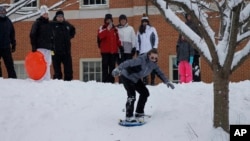 A group of adults and children enjoy an afternoon of sledding and snowboarding on a hill on the campus of Wake Forest University in Winston-Salem, N.C., Jan. 17, 2018. 