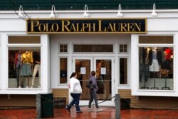 Women read a notice announcing the temporary closure of a Polo Ralph Lauren store in Freeport, Maine, March 17, 2020.