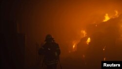 Seorang pemadam kebakaran bekerja memadamkan api di sebuah pabrik tembakau yang terbakar akibat serangan drone Rusia di Kyiv, Ukraina, pada 28 Mei 2023. (Foto: Pavlo Petrov/Press service of the State Emergency Service of Ukraine/Handout via Reuters)