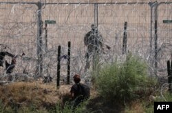 Seorang migran yang mencari suaka di Amerika Serikat diawasi oleh Garda Nasional Texas setelah menyeberangi Sungai Rio Grande, terlihat dari Ciudad Juárez, Negara Bagian Chihuahua, Meksiko, pada 5 Juni 2024. (Foto: AFP)