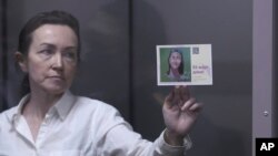 Алсу Курмашевій, редакторці Татаро-башкирської служби Радіо Свобода, присуджено премію Девіда Берка за журналістську за мужність і рішучість. На фото Алсу тримає поштівку зі закликом її звільнити під час судового засідання. Казань, Росія, 1 квітня 2024 року. (AP)