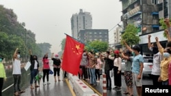 Anti-coup protesters hold a Chinese flag before burning it down during a demonstration against China in Yangon, Myanmar, April 5, 2021. 