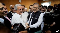 Mamnoon Hussain, center right, a presidential candidate from ruling party Pakistan Muslim League-N shakes hands with Raza Rabbani, a candidate from opposition party Pakistan People Party in Islamabad, July 24, 2013. 