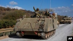 Tentara Israel mengacungkan tinju mereka dari kendaraan pengangkut personel lapis baja yang bergerak di Israel utara dekat perbatasan Israel-Lebanon, Selasa, 1 Oktober 2024. (Baz Ratner/AP)