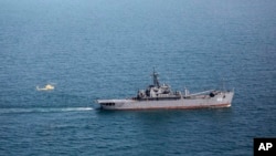 In this photo provided Feb. 22, 2025, by the Iranian Army, a helicopter approaches a vessel during a drill in the Gulf of Oman and the Indian Ocean.