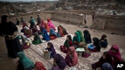 Anak-anak pengungsi Afghanistan mengulang angka yang ditampilkan oleh guru mereka selama kelas mereka di sebuah sekolah darurat yang didirikan di sebuah masjid. (Foto: AP)